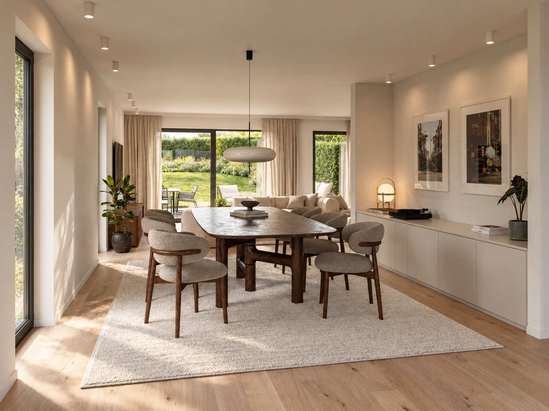 Salle à manger avec table ovale en bois foncé, six chaises, suspension et baies vitrées donnant sur le jardin.