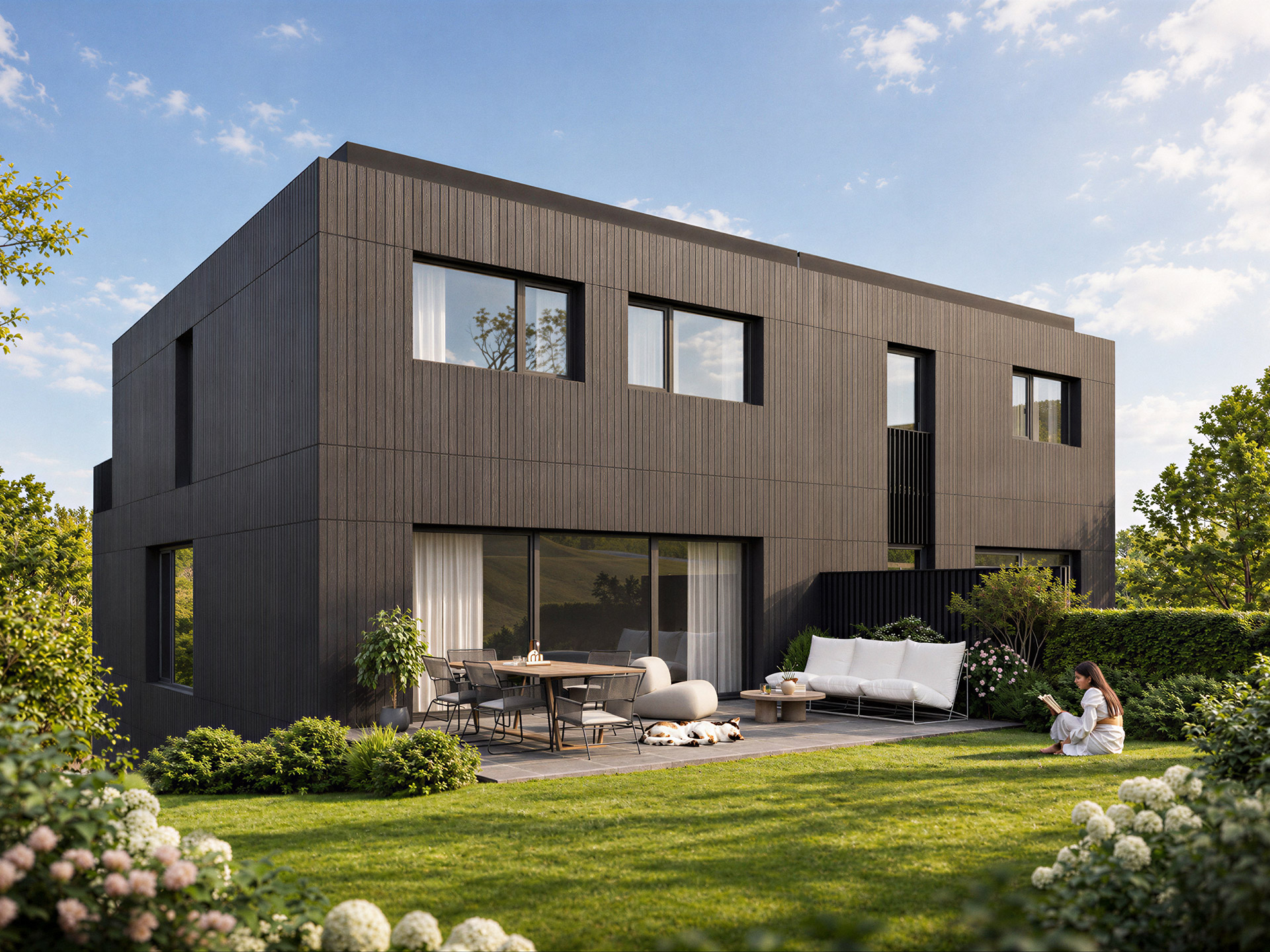 Façade arrière d'une maison Op Pelgert : bardage sombre, baies vitrées, terrasse avec salon de jardin et grande pelouse.